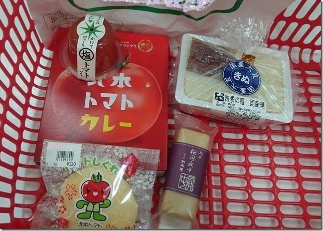 赤い買い物かごの中に北本トマトカレー、しぐれ、豆腐、最中などが入っている写真